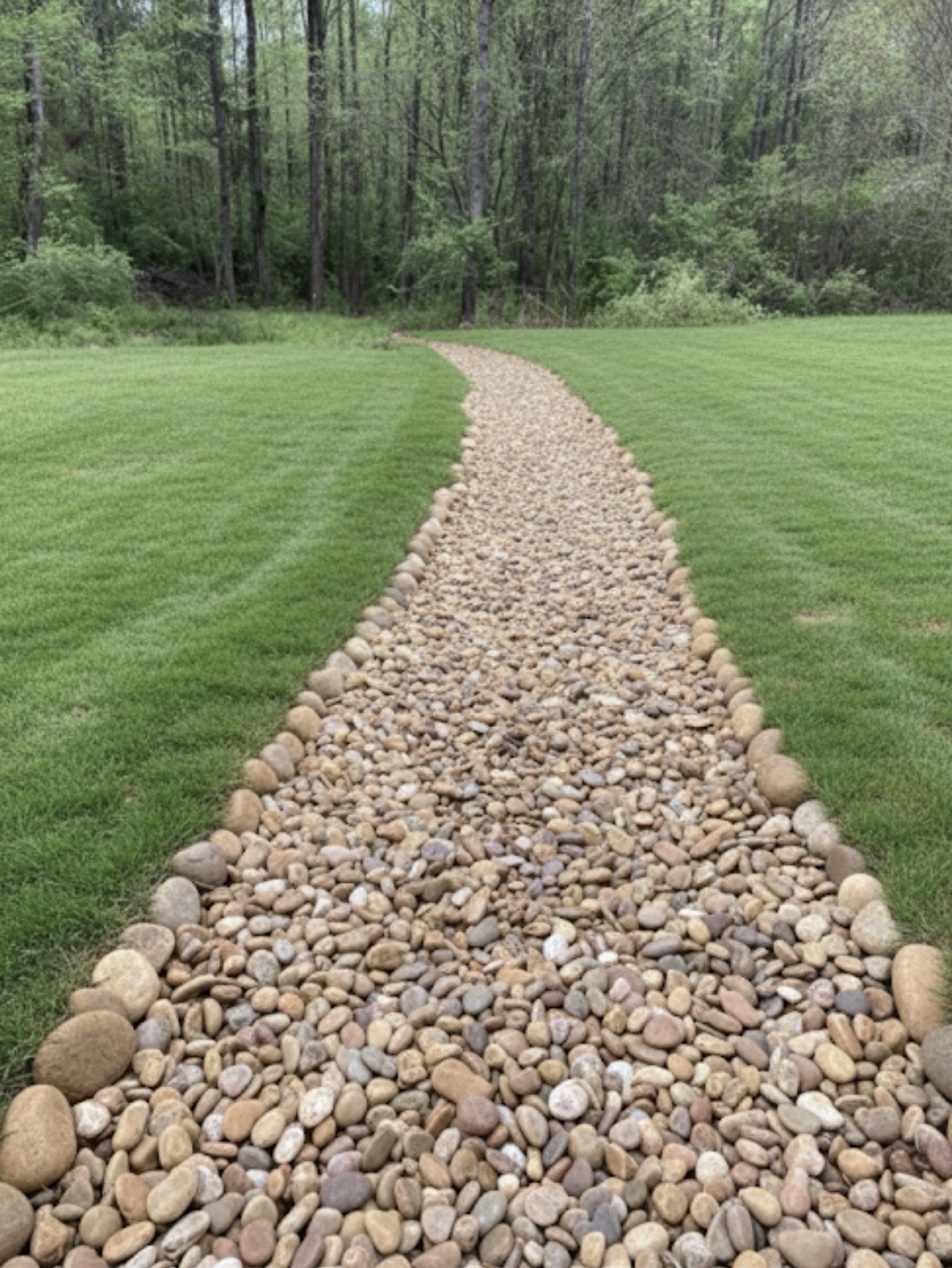 Finished creek bed drainage system with clean stone and proper grading for long-term water control.